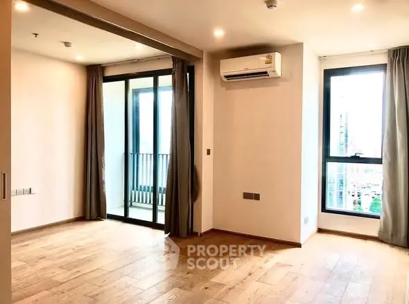 Spacious modern living room with wooden flooring and balcony access in a bright apartment.