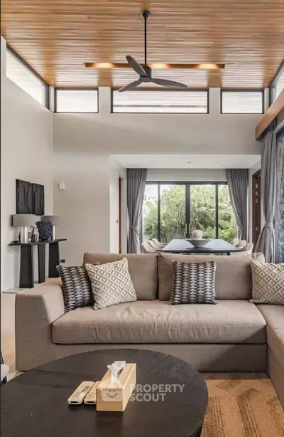 Luxurious modern living room with stylish decor and large windows overlooking greenery.