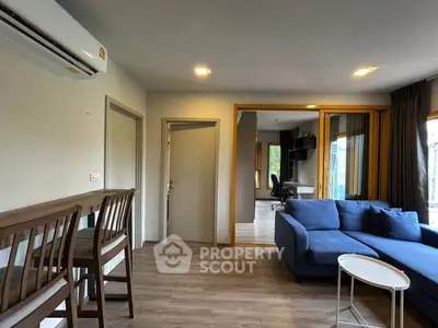 Modern living room with blue sofa and wooden flooring, featuring a stylish open layout.