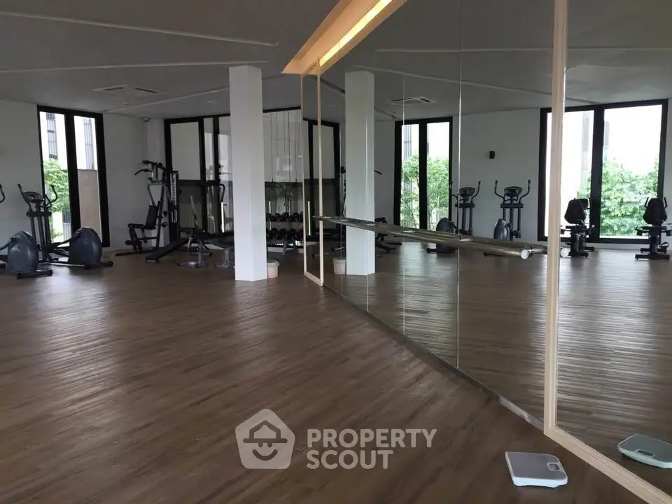Spacious gym with modern equipment and mirrored walls in luxury residential building.