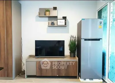 Modern living room with sleek TV stand, wall shelves, and stainless steel fridge.