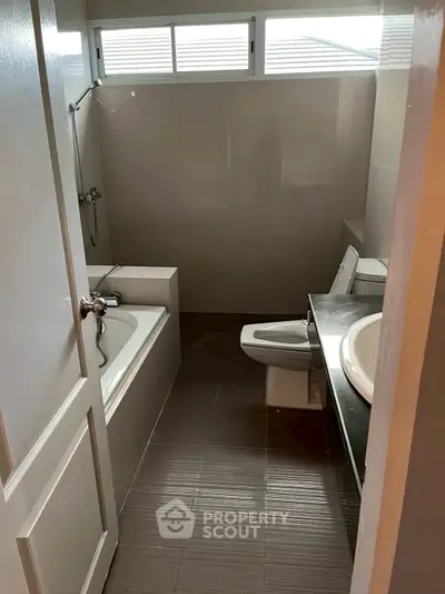 Compact bathroom with bathtub and modern fixtures, ideal for efficient space utilization.