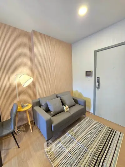Modern living room with stylish sofa, striped rug, and wooden accent wall in cozy apartment.