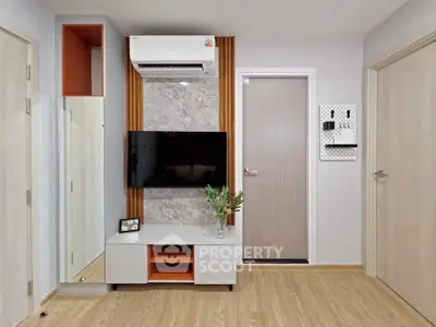 Modern living room with sleek TV setup and stylish decor, featuring wooden flooring and air conditioning.