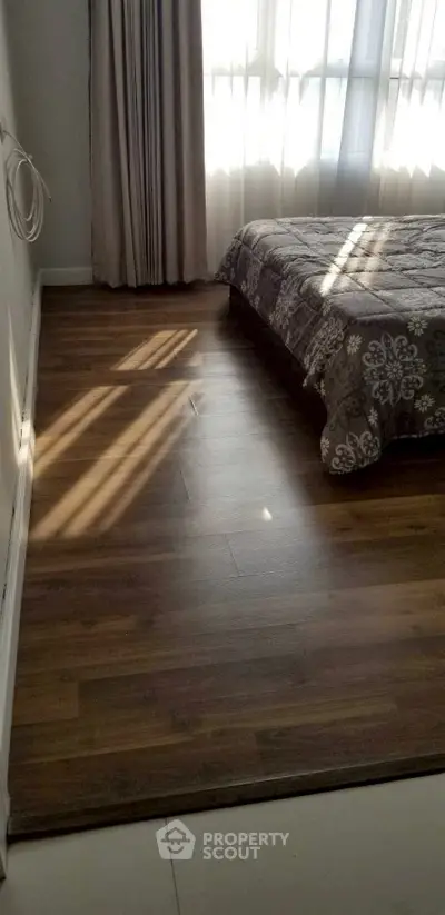 Cozy bedroom with wooden flooring and natural light