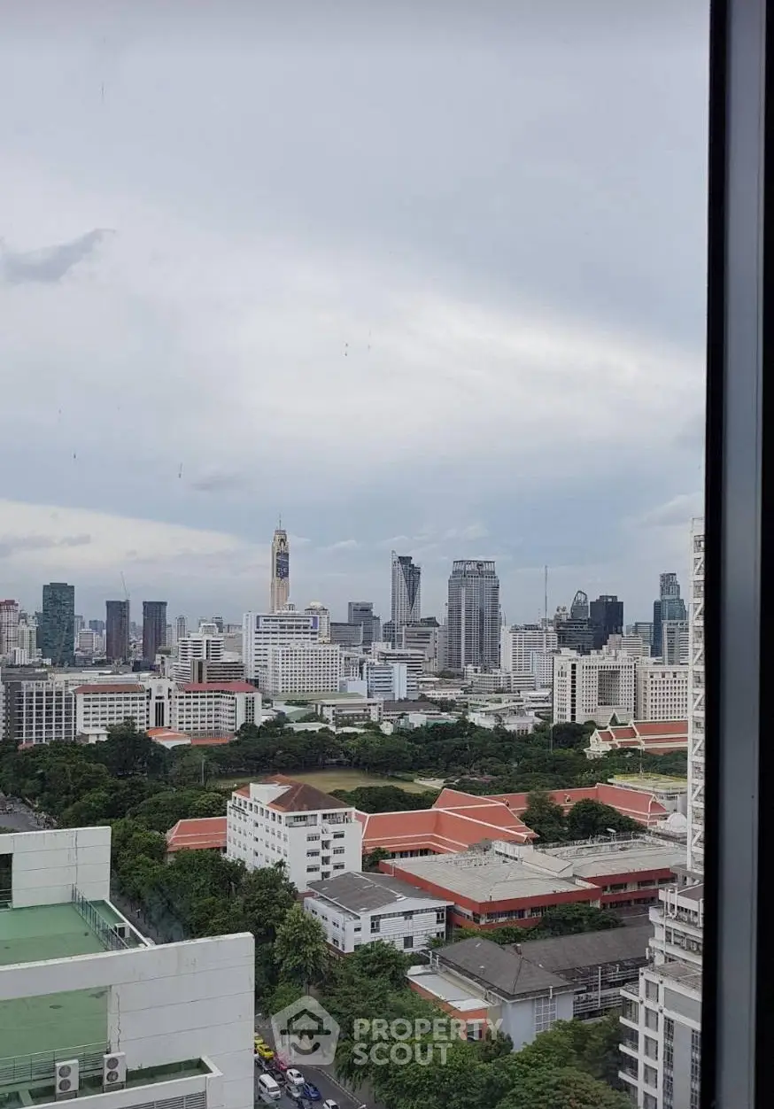 Stunning cityscape view from high-rise building window showcasing urban skyline and lush greenery.