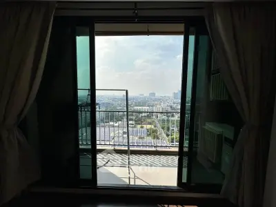 Stunning city view from a high-rise balcony with sliding glass doors and curtains.