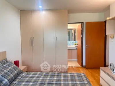 Cozy bedroom with wooden wardrobe and ensuite bathroom in modern apartment