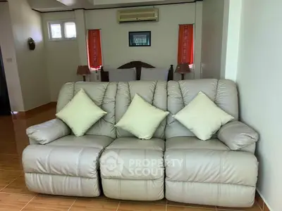 Spacious living room with plush leather sofa and cozy bedroom view