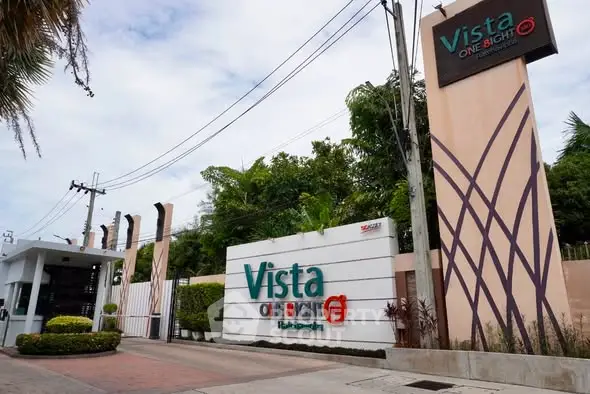 Modern residential entrance with stylish signage and lush greenery.