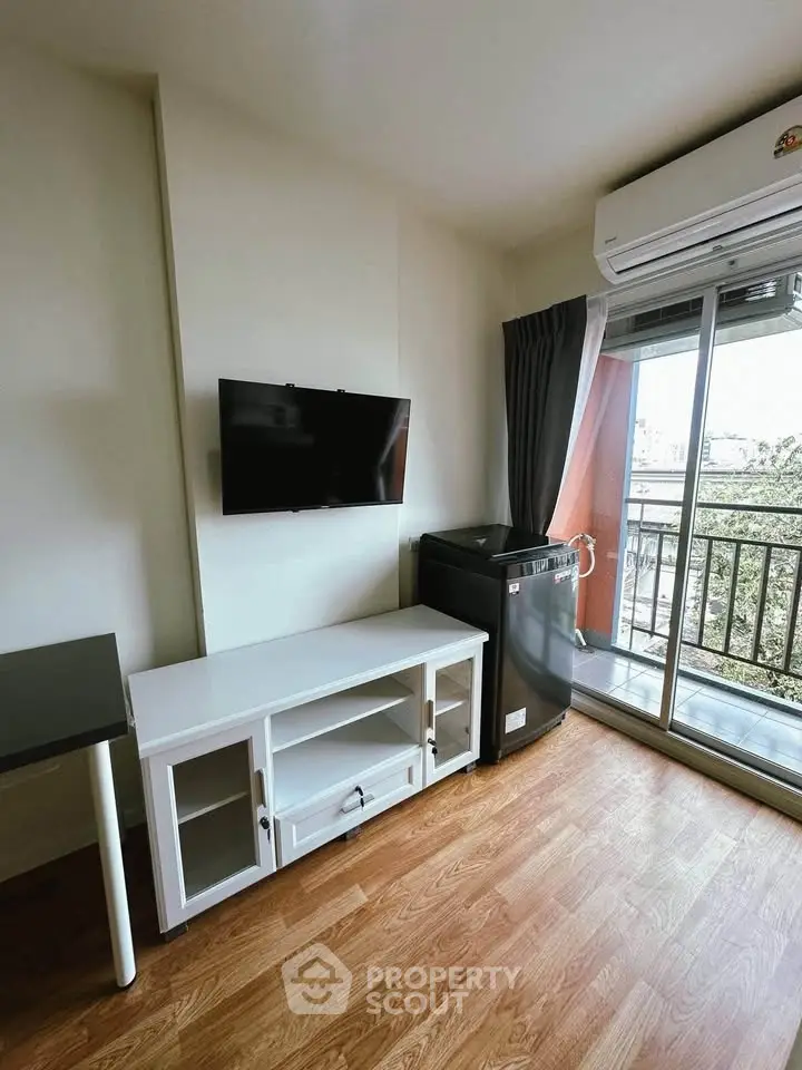 Modern living room with balcony, TV, and washing machine in a stylish apartment.