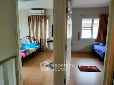 Charming dual-bedroom setup with wooden flooring and natural light.