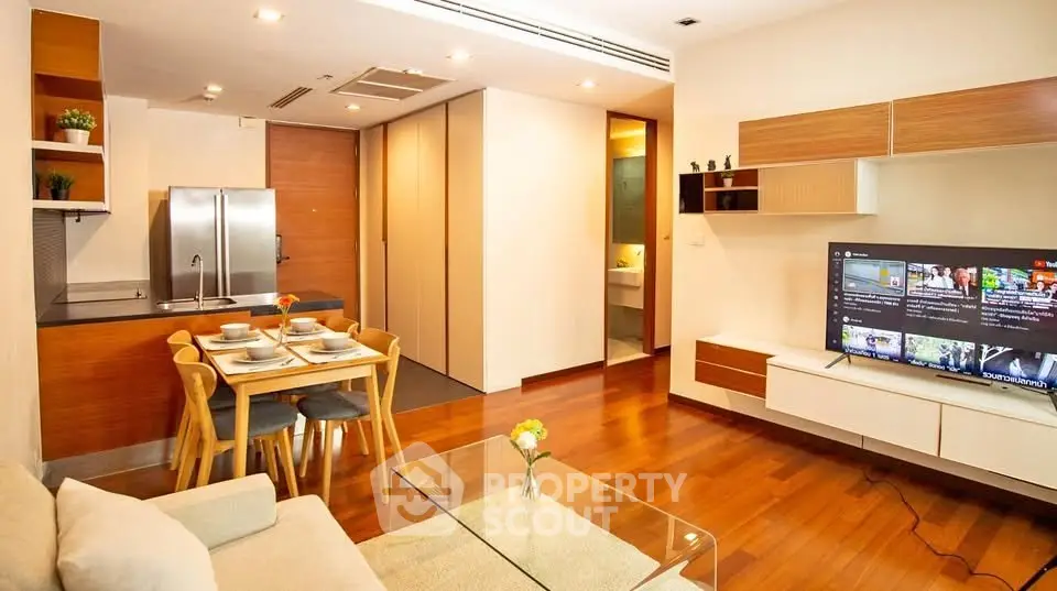 Modern open-plan living room with sleek kitchen and dining area, featuring wooden flooring and stylish decor.