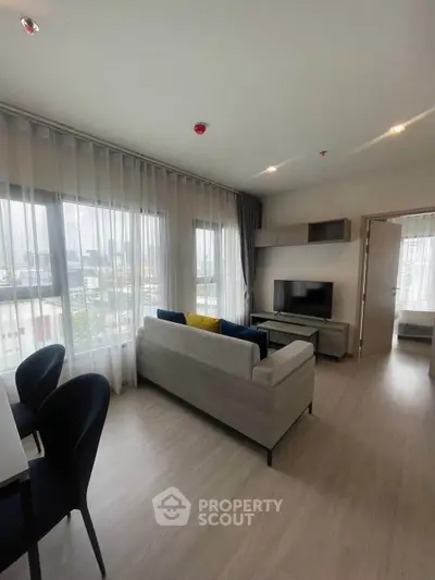 Modern living room with large windows and stylish furniture in a high-rise apartment.