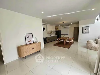 Spacious modern living room with open kitchen and dining area, featuring sleek furniture and bright lighting.