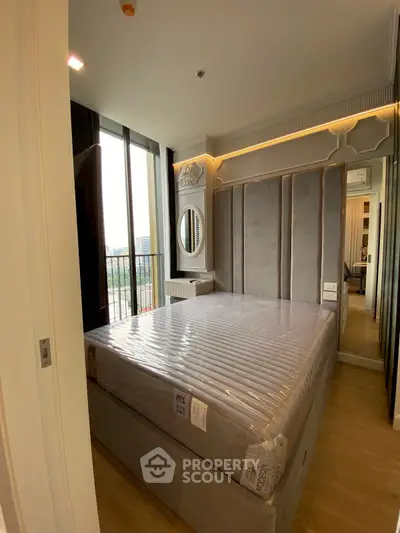 Modern bedroom with large bed and floor-to-ceiling windows offering city views