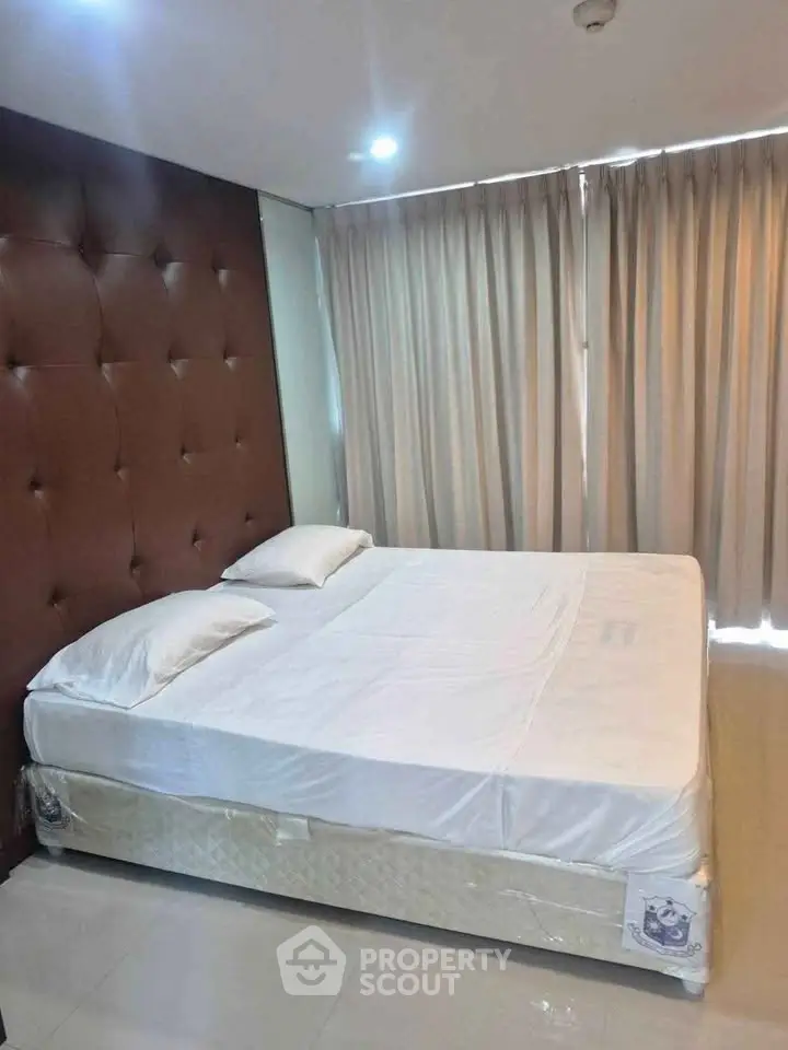 Spacious bedroom with elegant headboard and natural light through large windows.