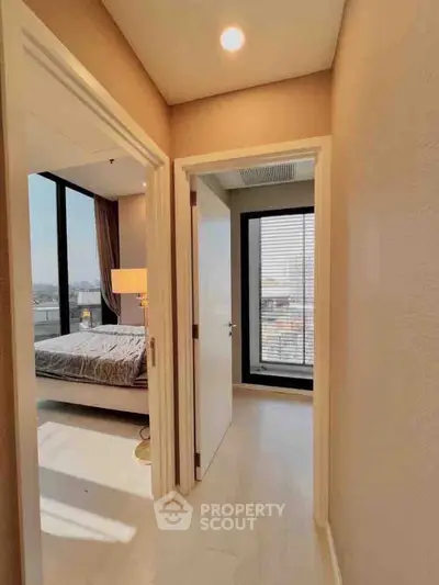 Bright hallway leading to a modern bedroom with large windows and natural light.