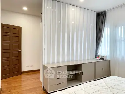 Modern bedroom with sleek storage and natural light, featuring wooden flooring and stylish decor.