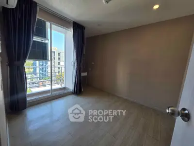 Spacious empty room with large window and balcony access in modern apartment.
