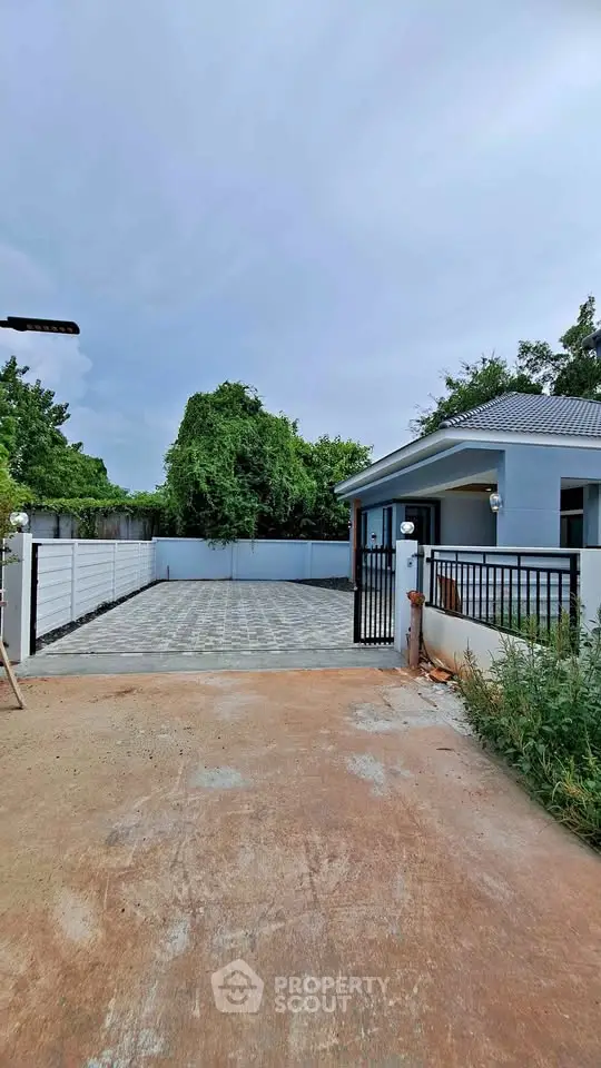 Charming single-story home with spacious driveway and lush greenery, perfect for serene living.