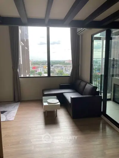 Modern living room with large window and city view, featuring sleek furniture and wooden flooring.