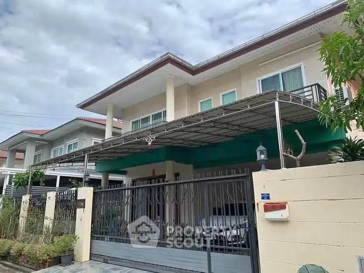 Modern two-story house with gated entrance and carport in suburban neighborhood.