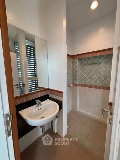 Compact bathroom with modern sink and tiled shower area