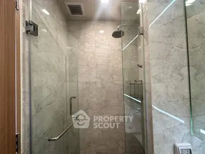 Modern bathroom with glass shower enclosure and marble walls