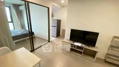 Modern apartment interior with open living room and bedroom, featuring sleek furniture and natural light.