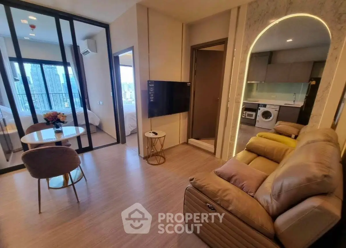 Modern apartment interior with open living room, kitchen, and city view from balcony.