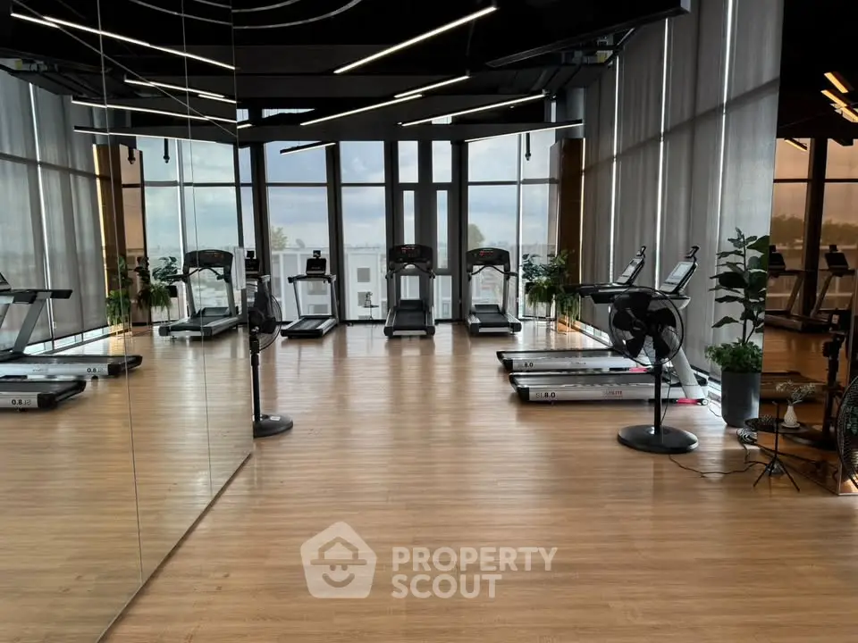 Spacious modern gym with treadmills and large windows offering a scenic view.