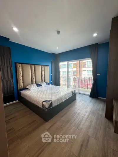 Spacious bedroom with modern decor and balcony access in a stylish apartment.