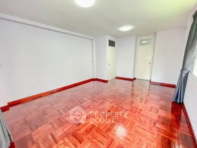 Spacious empty room with polished wooden floors and bright natural light