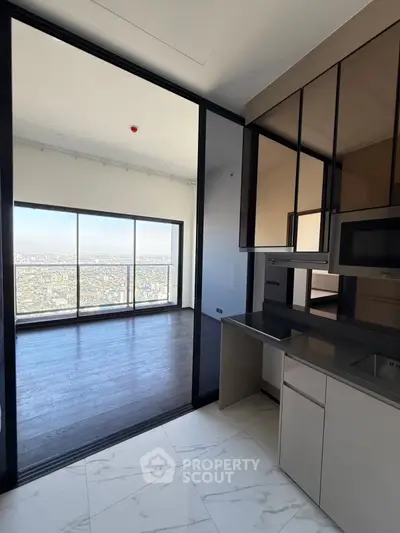Modern kitchen with sleek cabinetry and stunning city view from living area.