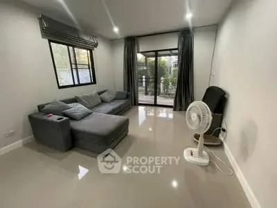 Spacious living room with modern gray sofa and large windows overlooking garden