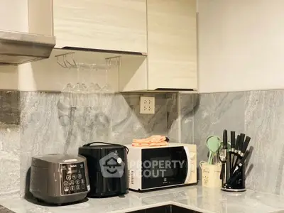 Modern kitchen with appliances including microwave and rice cooker on marble countertop.