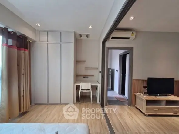 Modern bedroom with study area and TV, featuring sleek design and ample natural light.