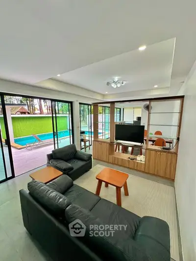 Modern living room with pool view and sleek black leather sofa