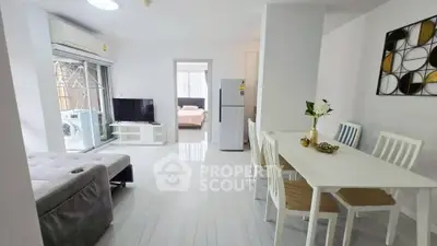 Modern open-plan living room with dining area and view into bedroom, featuring sleek furniture and bright decor.