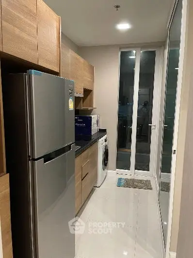 Modern kitchen with stainless steel fridge and washing machine in sleek apartment.