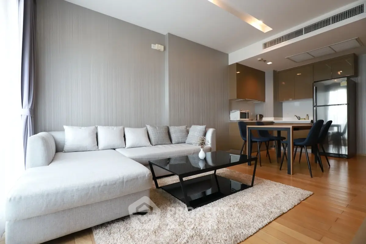 Modern open-layout living room with sleek kitchen, stylish furniture, and natural light.