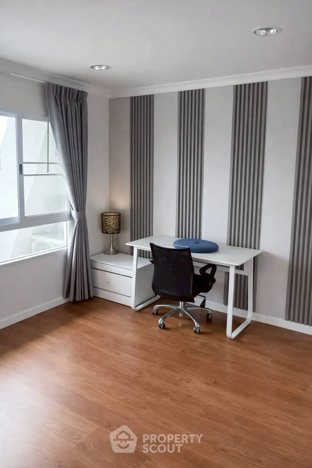 Modern study room with sleek desk and chair, featuring elegant striped wall design and natural light.