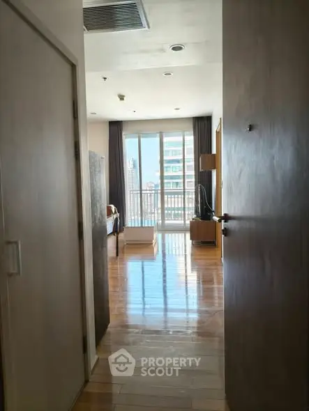 Spacious bedroom with large windows and city view, featuring elegant wooden flooring.