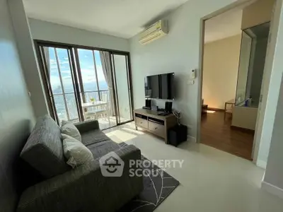 Modern living room with balcony and city view, featuring sleek furniture and natural light.