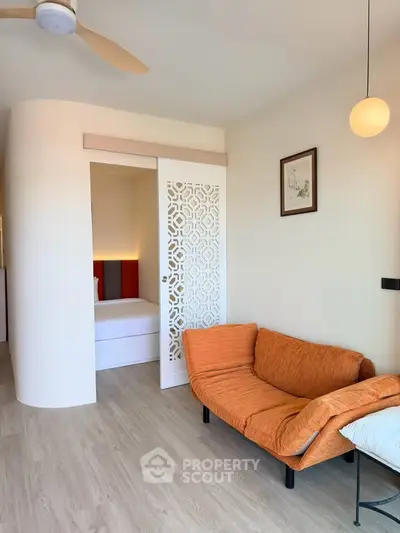 Modern living room with stylish orange sofa and decorative sliding door leading to bedroom.
