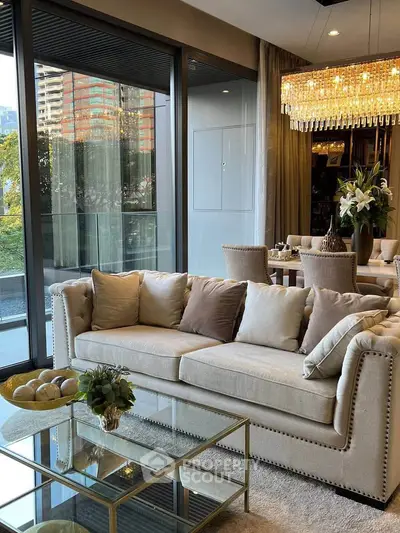 Luxurious living room with elegant chandelier and large windows offering stunning city views.