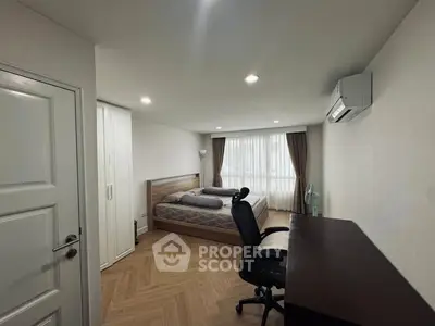 Modern bedroom with wooden flooring, desk, and air conditioning