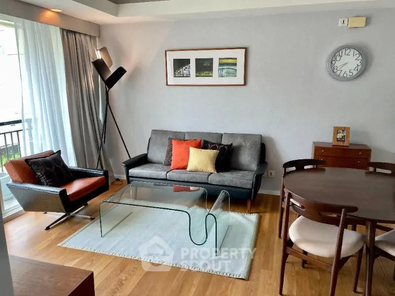 Stylish living room with modern furniture and glass coffee table, featuring a cozy ambiance and natural light.