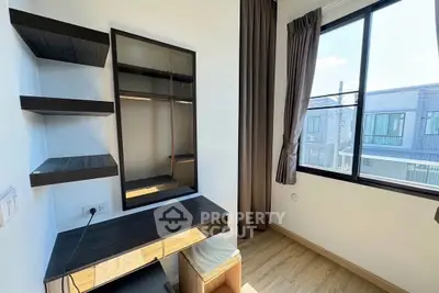 Modern study room with sleek desk and shelves, large window with natural light.